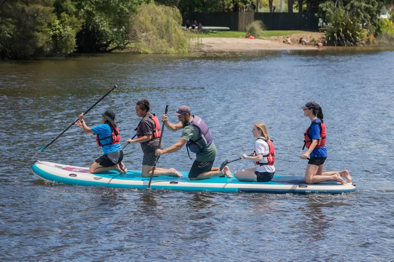 Five paddlers sharing one giant paddleboard