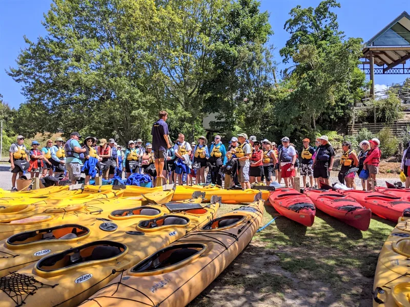 A large team lined up beside the kayaks, ready to go