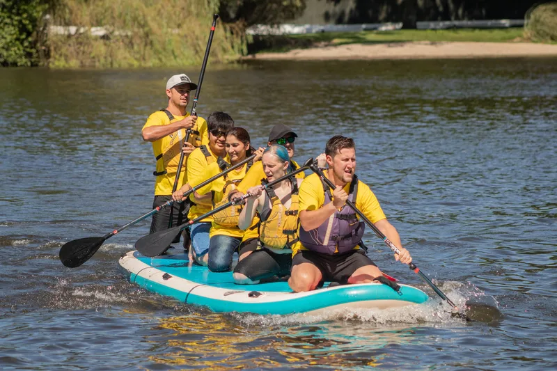 A team powering a giant paddleboard across the water